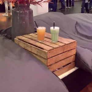 Zwei Getränke auf einem Holztisch, umgeben von gemütlichen Sitzkissen in einem modernen Ambiente.